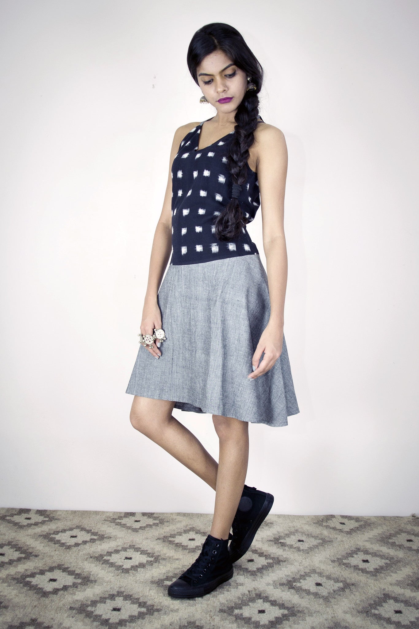 Model is wearing a Sundress in black white squared ikat and grey cotton.  It has a loose silhouette with up down hem and halter neck. In Cotton.