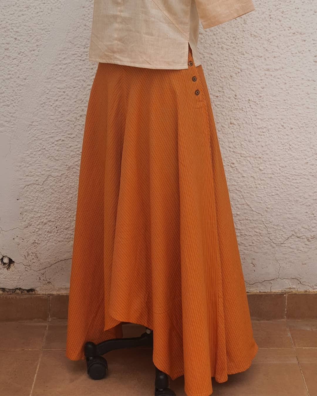 Picture of long asymmetrical skirt in orange stripes with a beige crop top