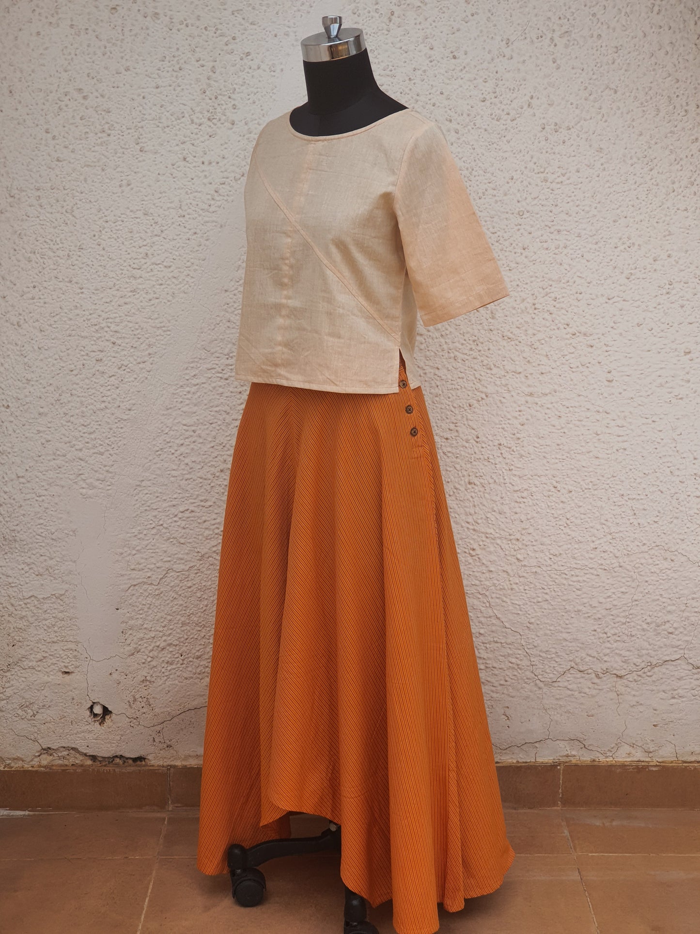 Picture of long asymmetrical skirt in orange stripes with a beige crop top