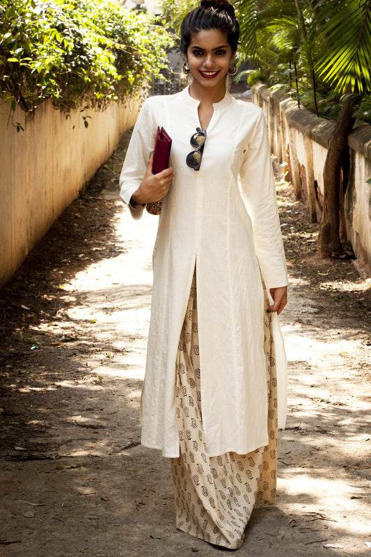 Picture of woman in off white kurta paired with a long beige skirt.
