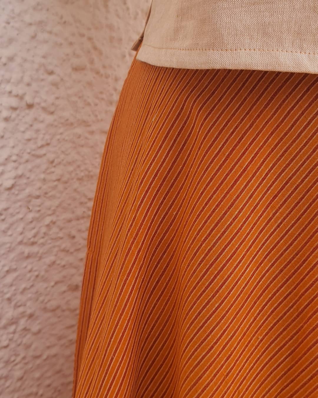 Picture of close up of skirt in orange stripes with a beige crop top