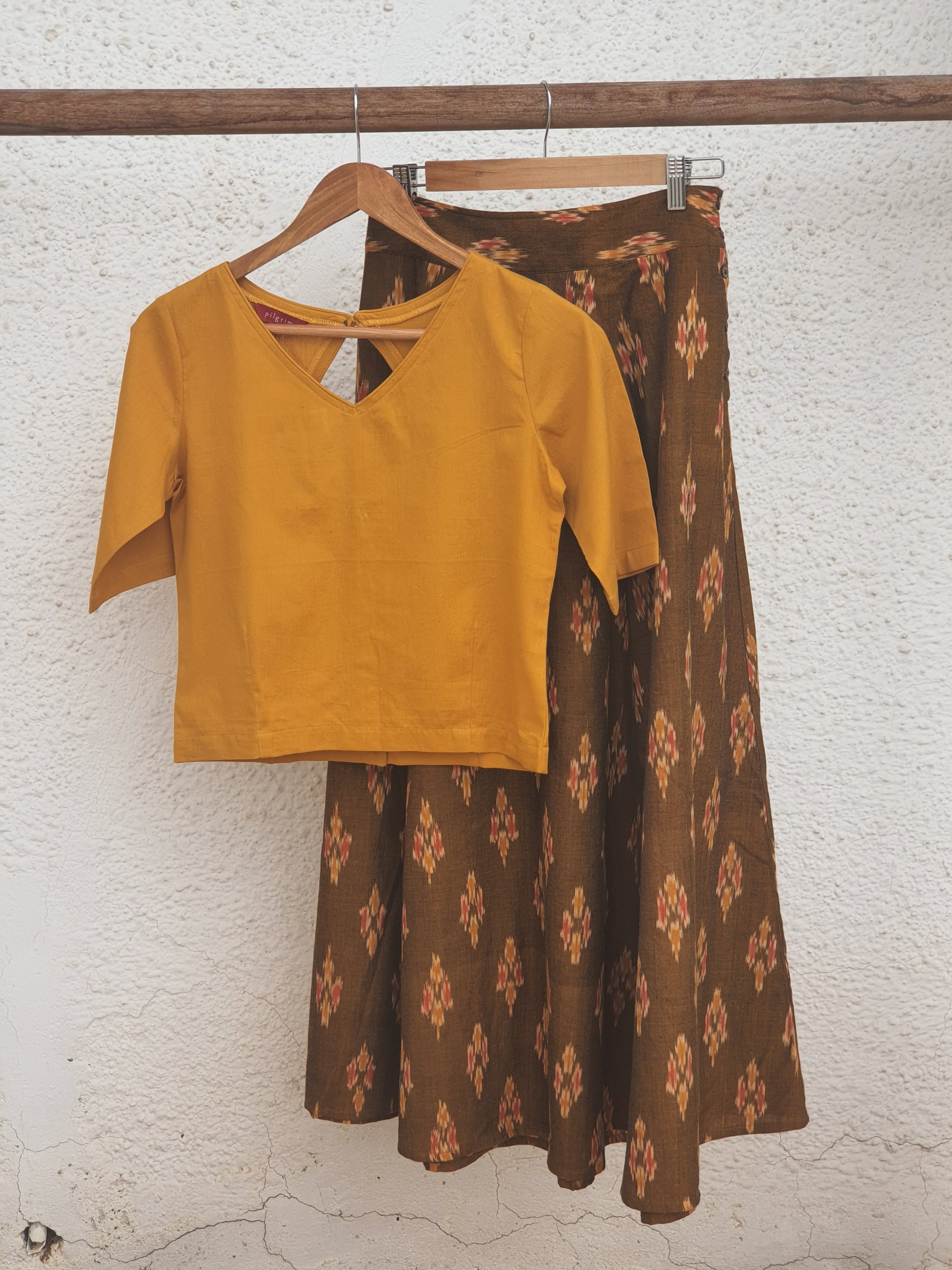 picture of a crop top in haldi colour paired with a long skirt in caramel ikkat